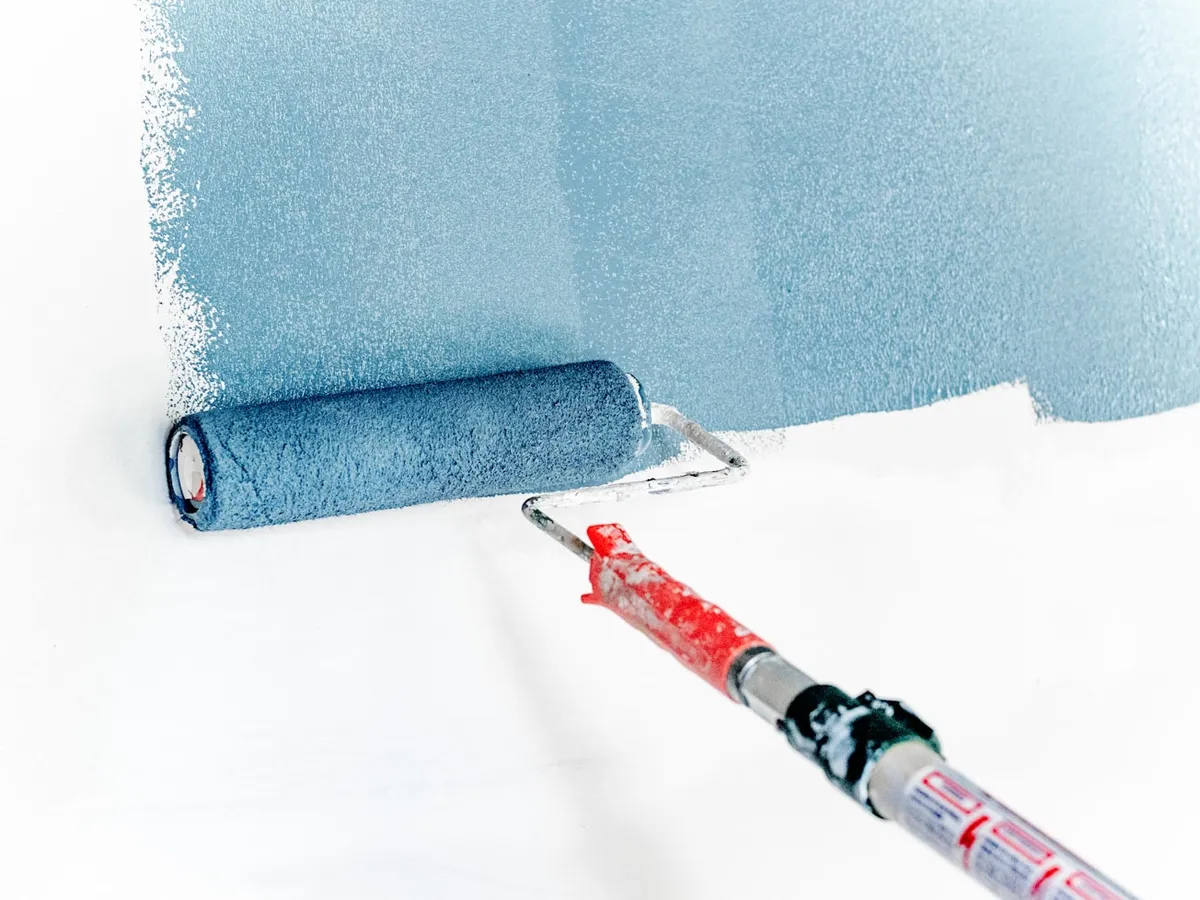 Profesional aplicando pintura y preparando una pared interior